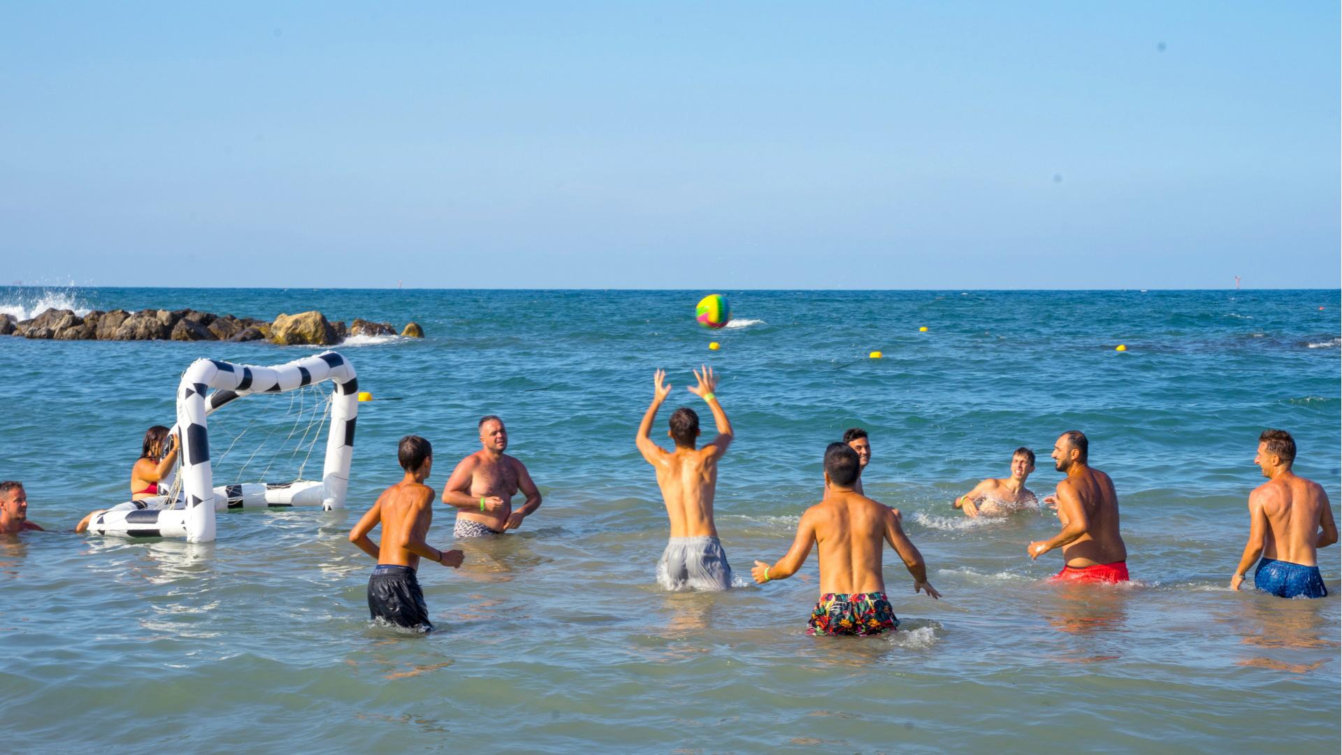 Persone giocano a palla in mare con una porta gonfiabile.