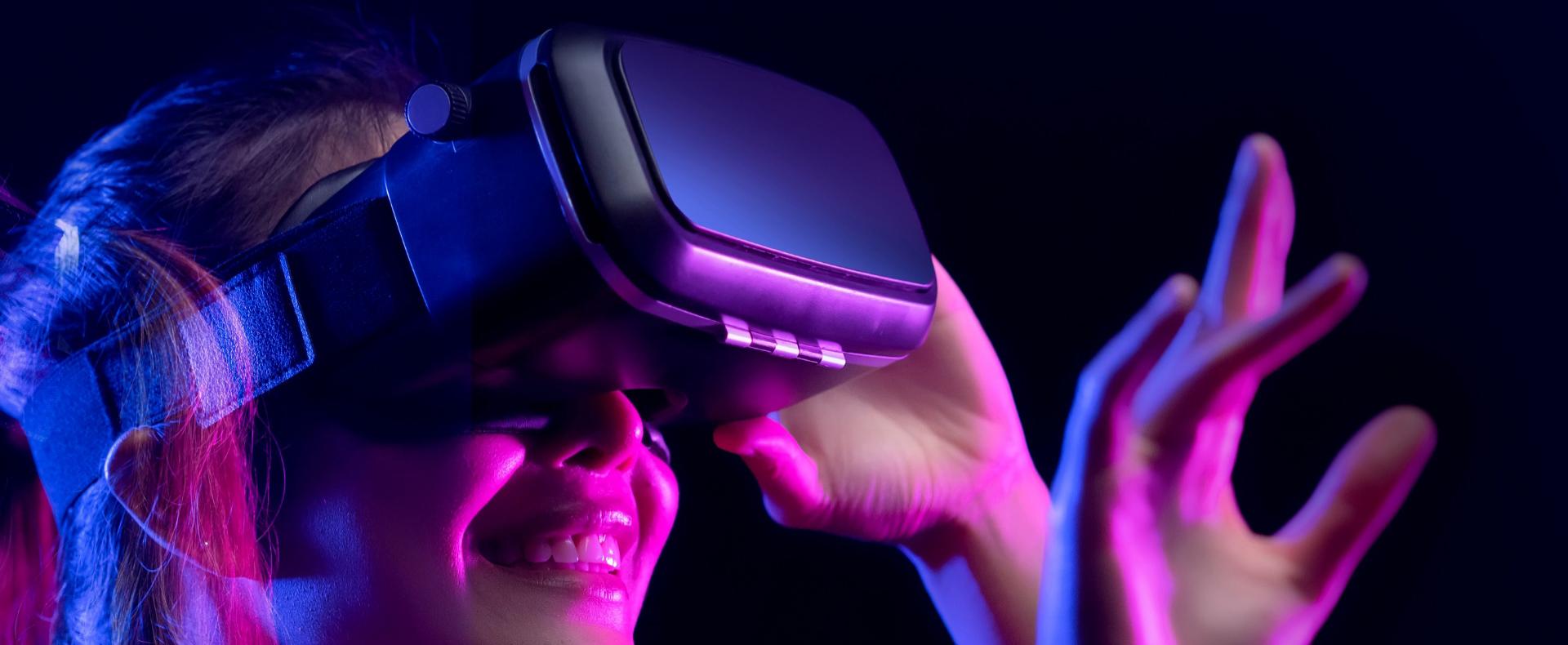 Persona con visore VR immersa in un'esperienza virtuale, illuminata da luci colorate.