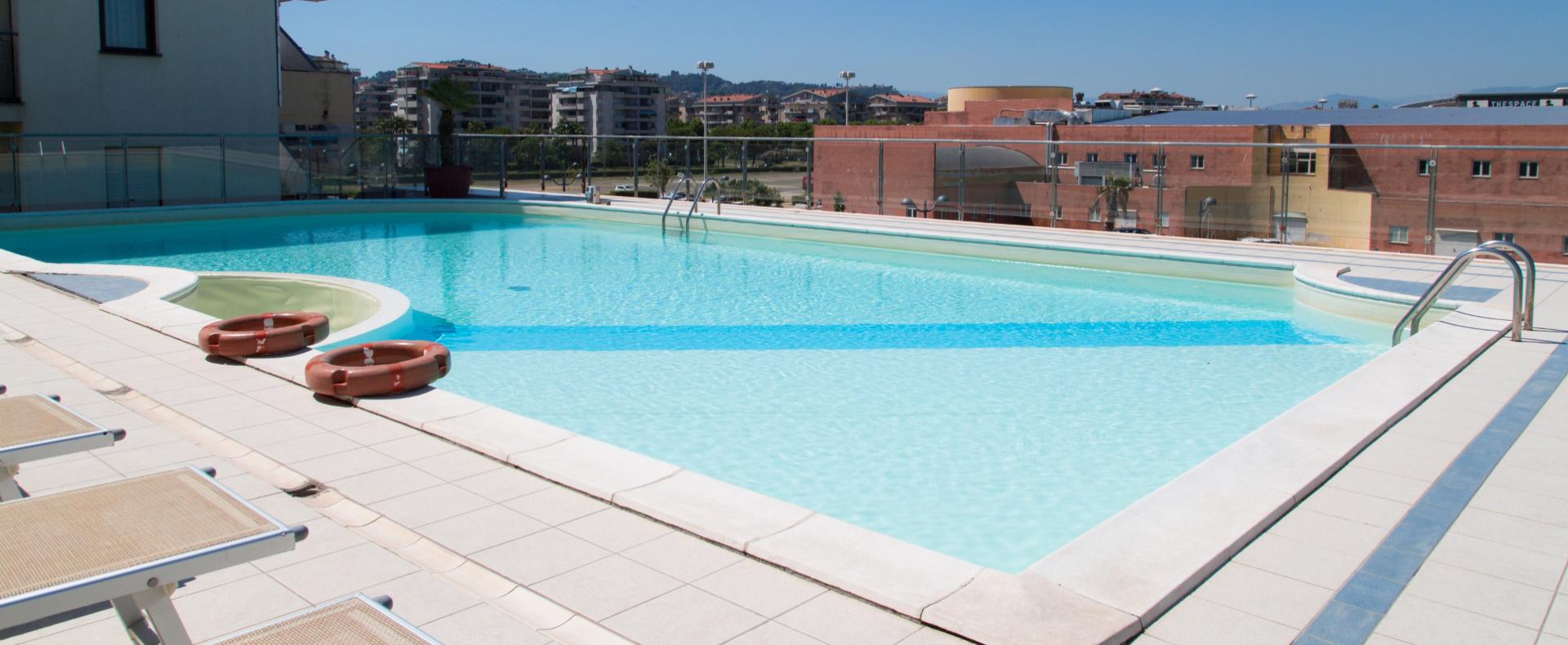 Piscina sul tetto con vista sulla città e lettini prendisole.